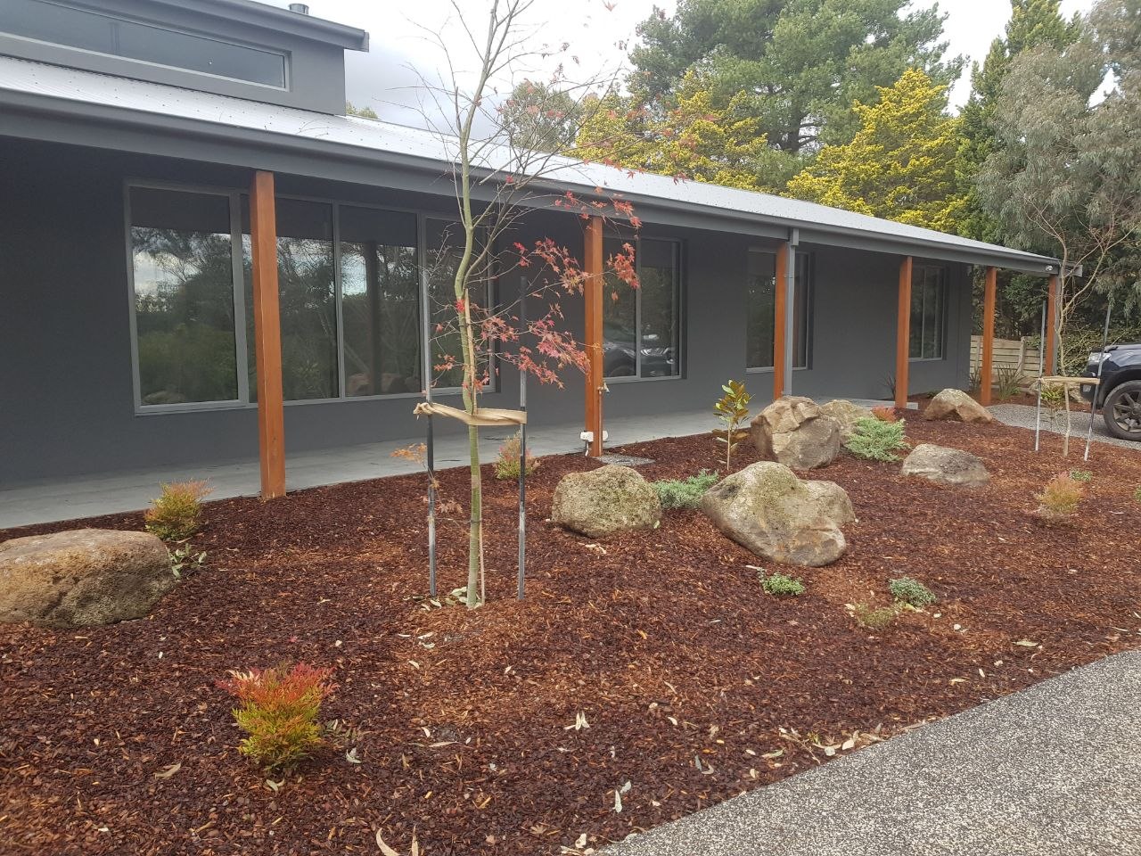 Charcoal acrylic rendered home with timber posts and landscaped garden, Melbourne VIC