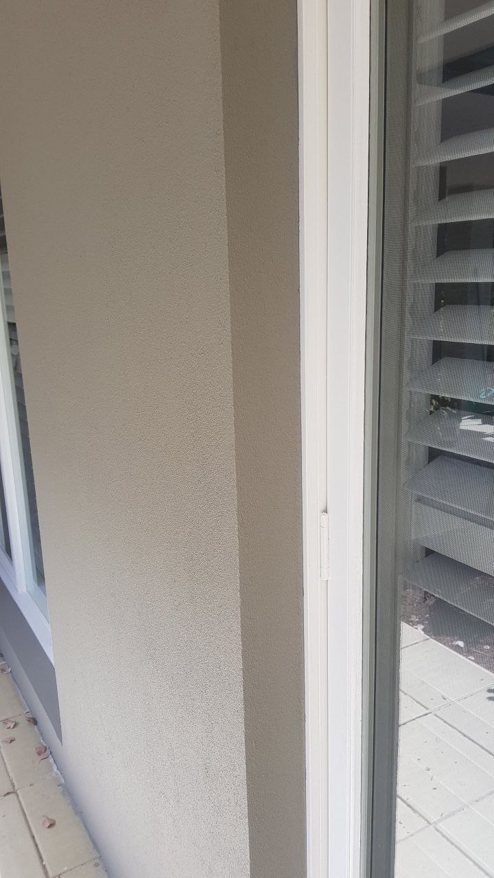 Smooth grey acrylic rendered wall beside sliding door with crisp paint line, Melbourne VIC
