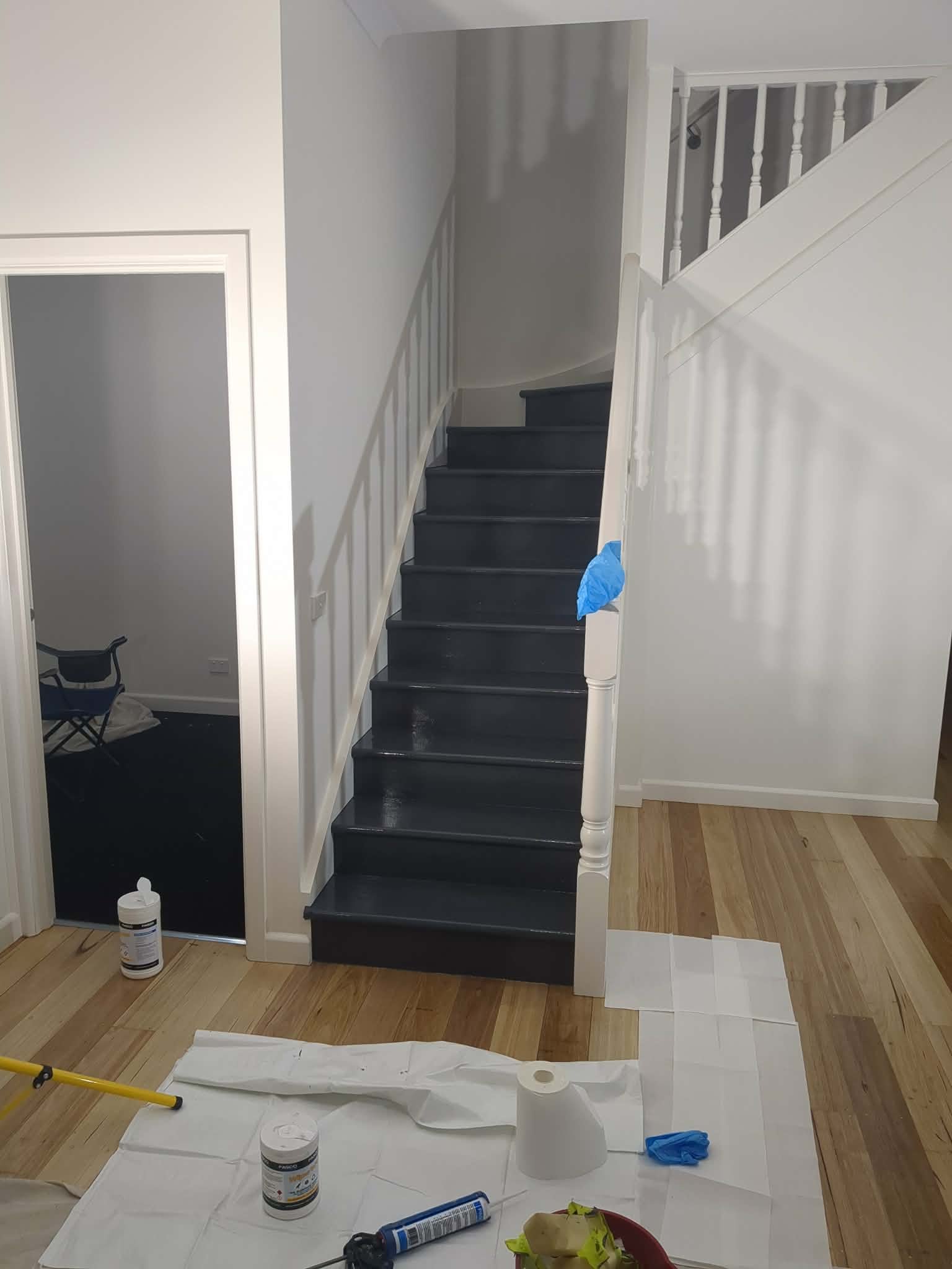 Newport staircase part-way through restoration, with freshly painted treads, masked balustrade and drop sheets across the hallway floor