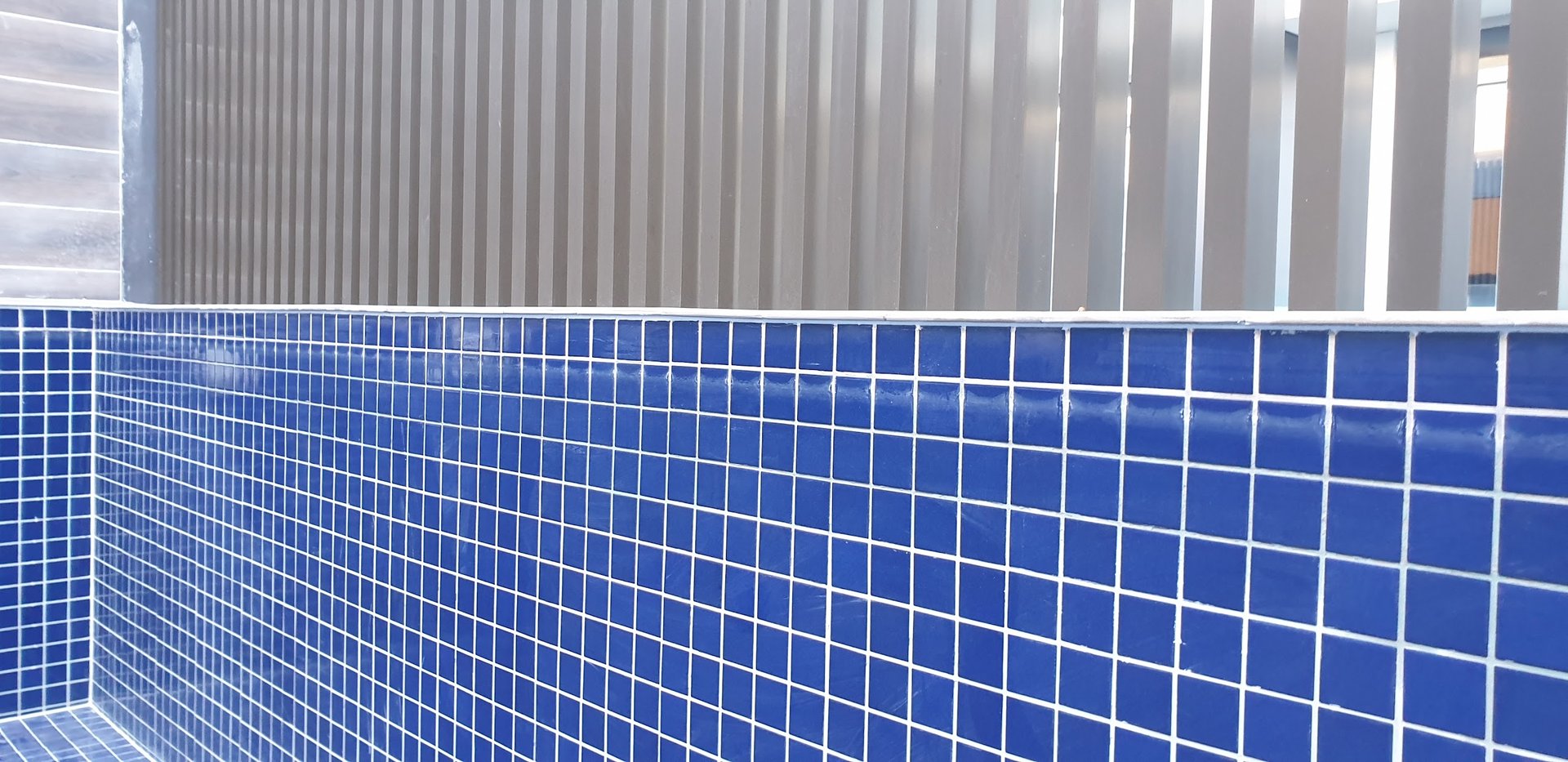 Finished blue mosaic tiled surface alongside boundary fencing