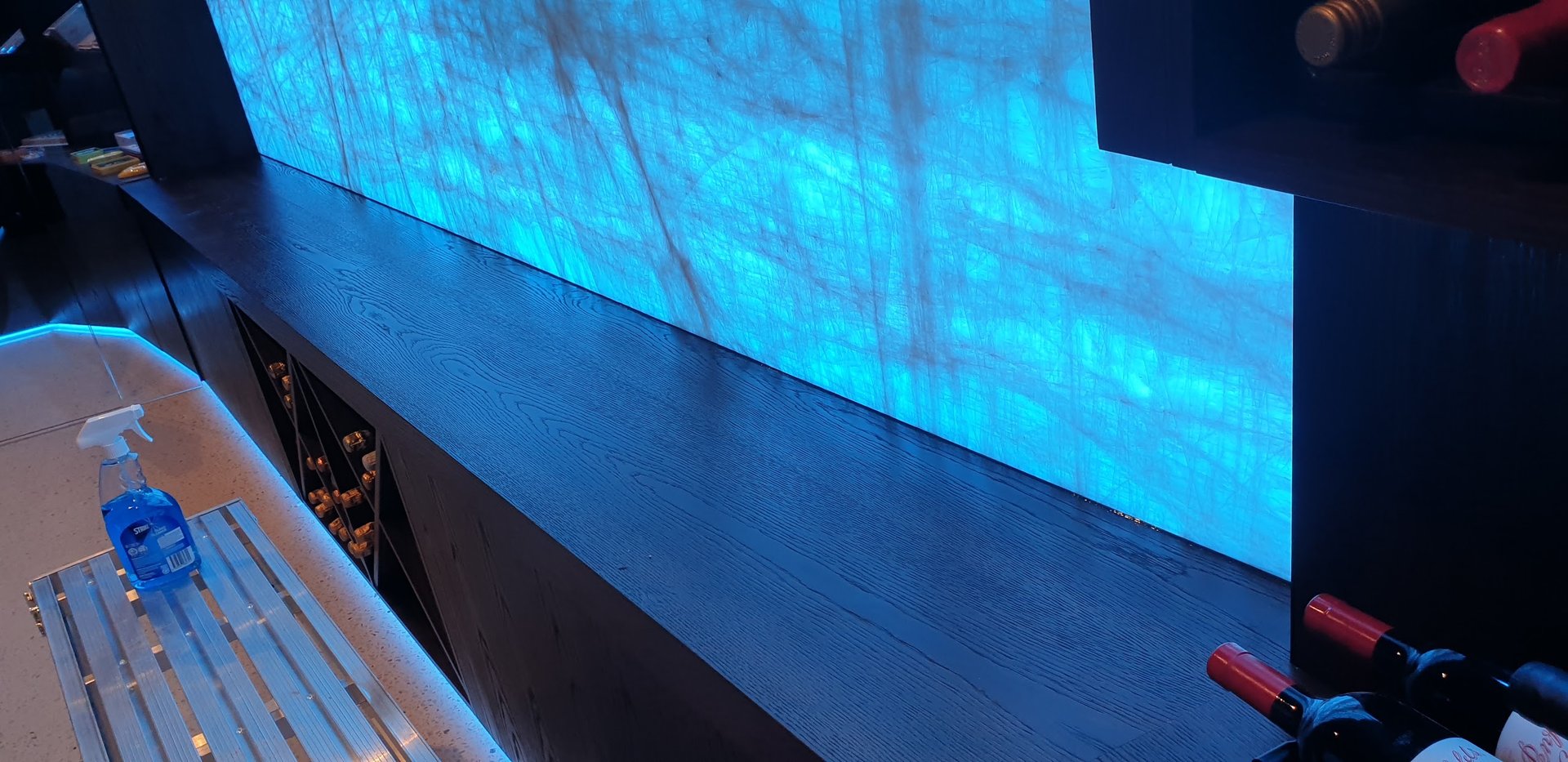 Backlit stone feature wall behind a bar benchtop during finishing work