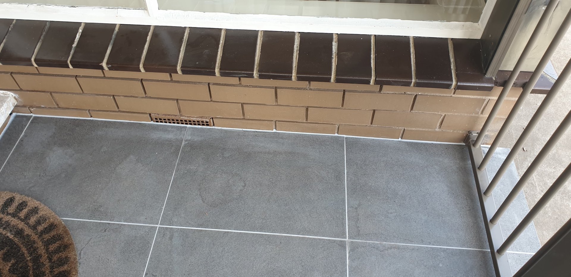 Completed tiled outdoor floor area beside a brick home