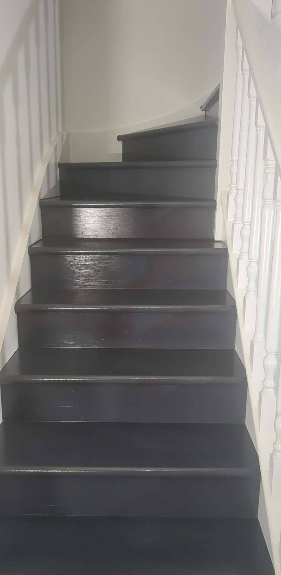 Completed staircase after painting, with dark treads and risers and white balustrade and surrounding walls