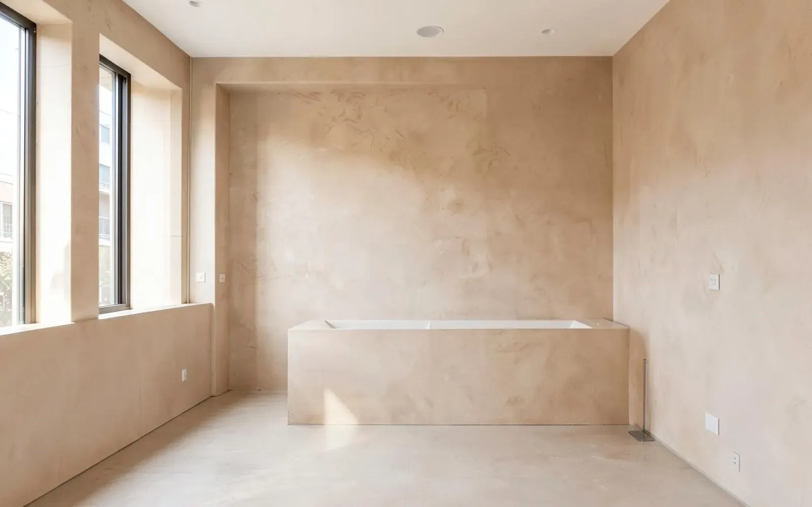 Interior room with seamless hand-applied plaster wall and floor finishes in a warm neutral tone